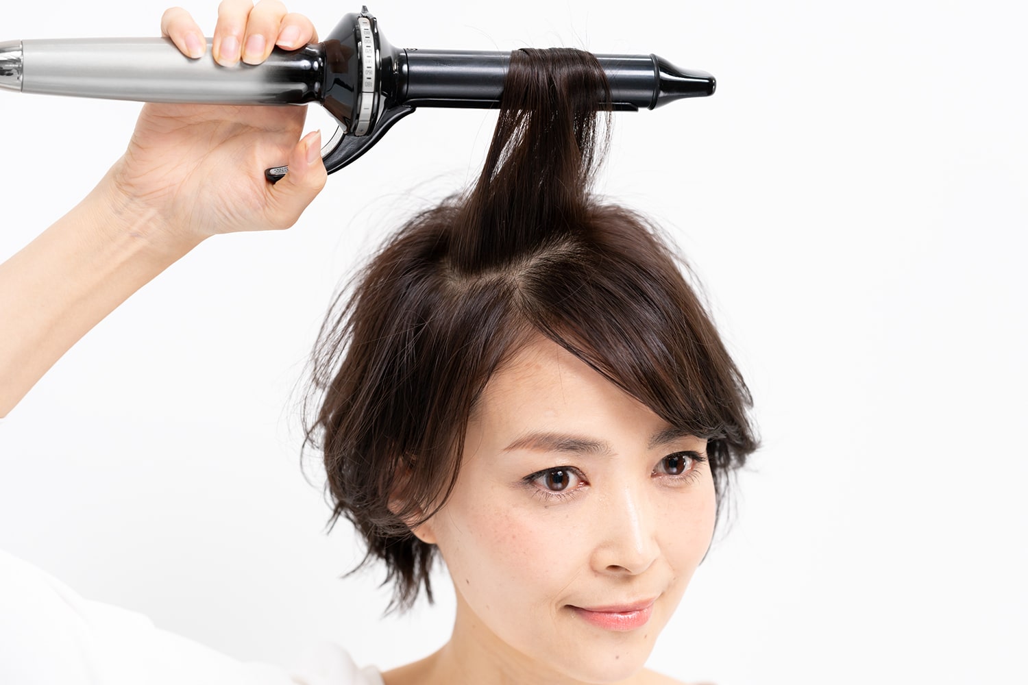 分け目をまたぐように毛束を取り、毛先だけ1カールさせる。