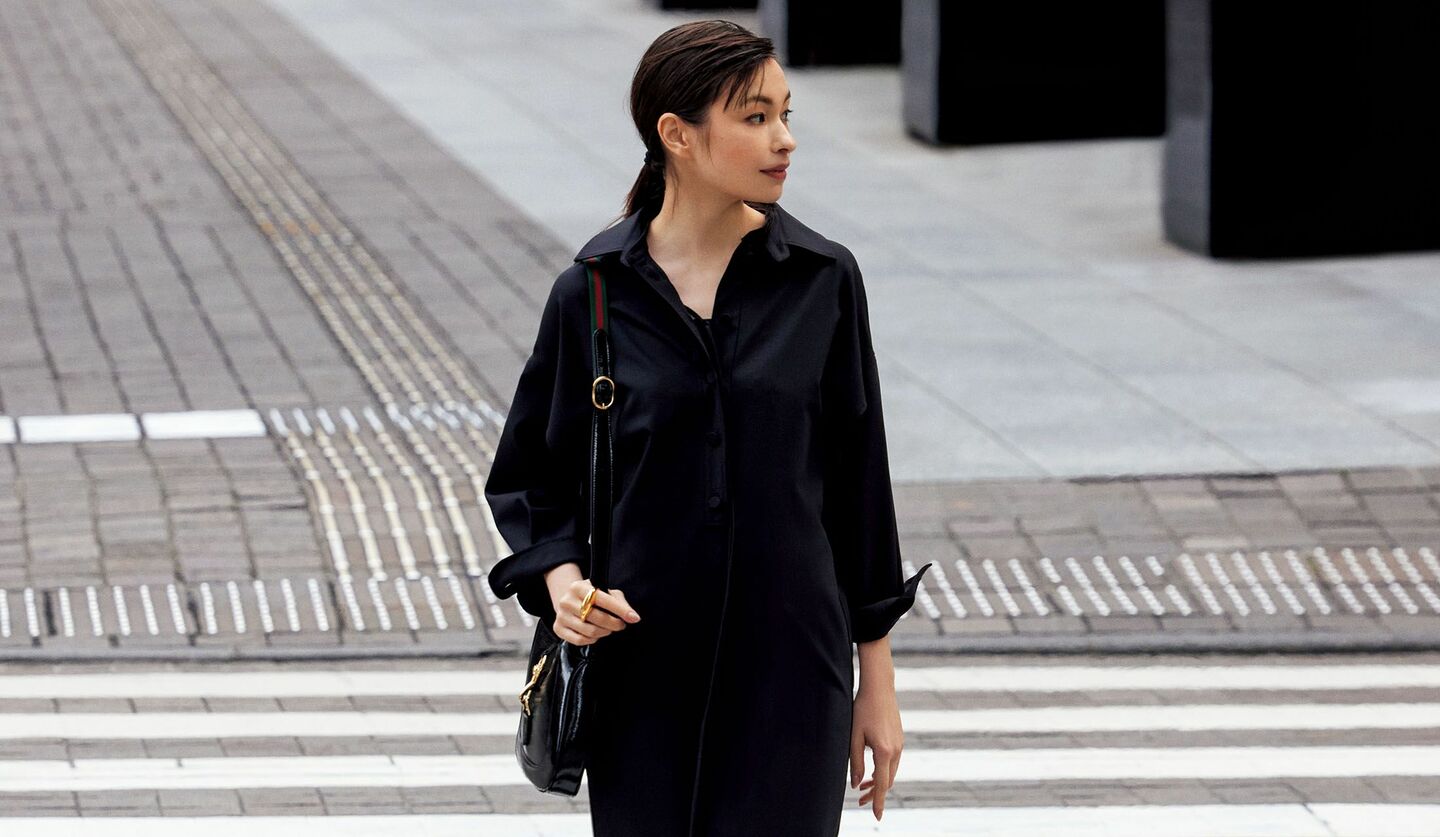 黒い襟付きワンピースを着て、横断歩道を渡っているモデルの写真