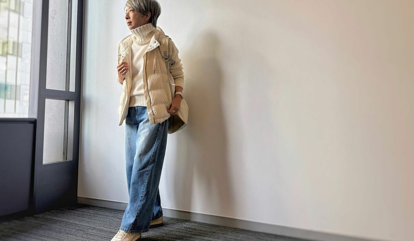 白ニットに白のダウンベストを重ね、デニムを合わせたコーディネート