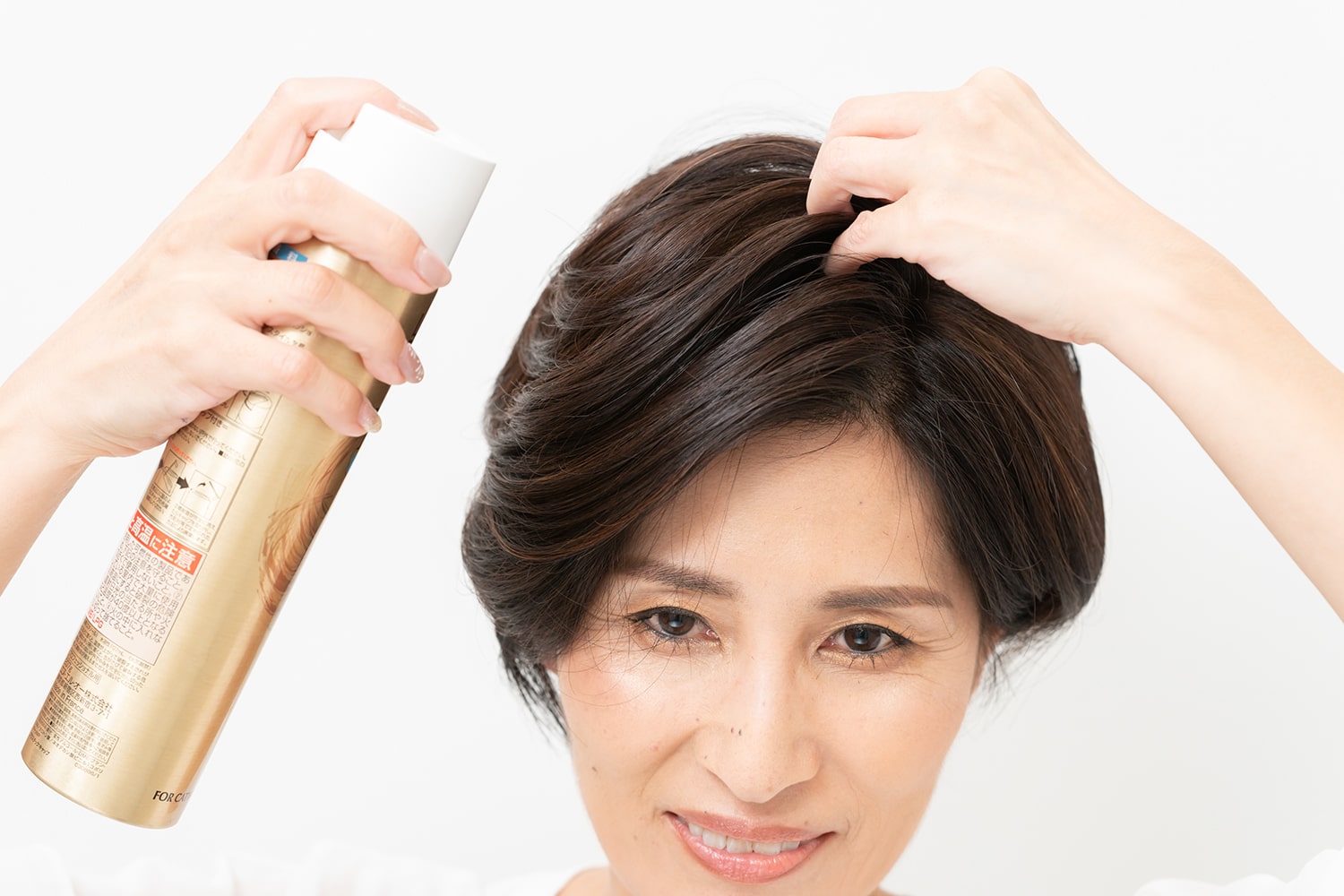 分け目付近の髪をつかみ、根元を立たせるようにスプレーを。