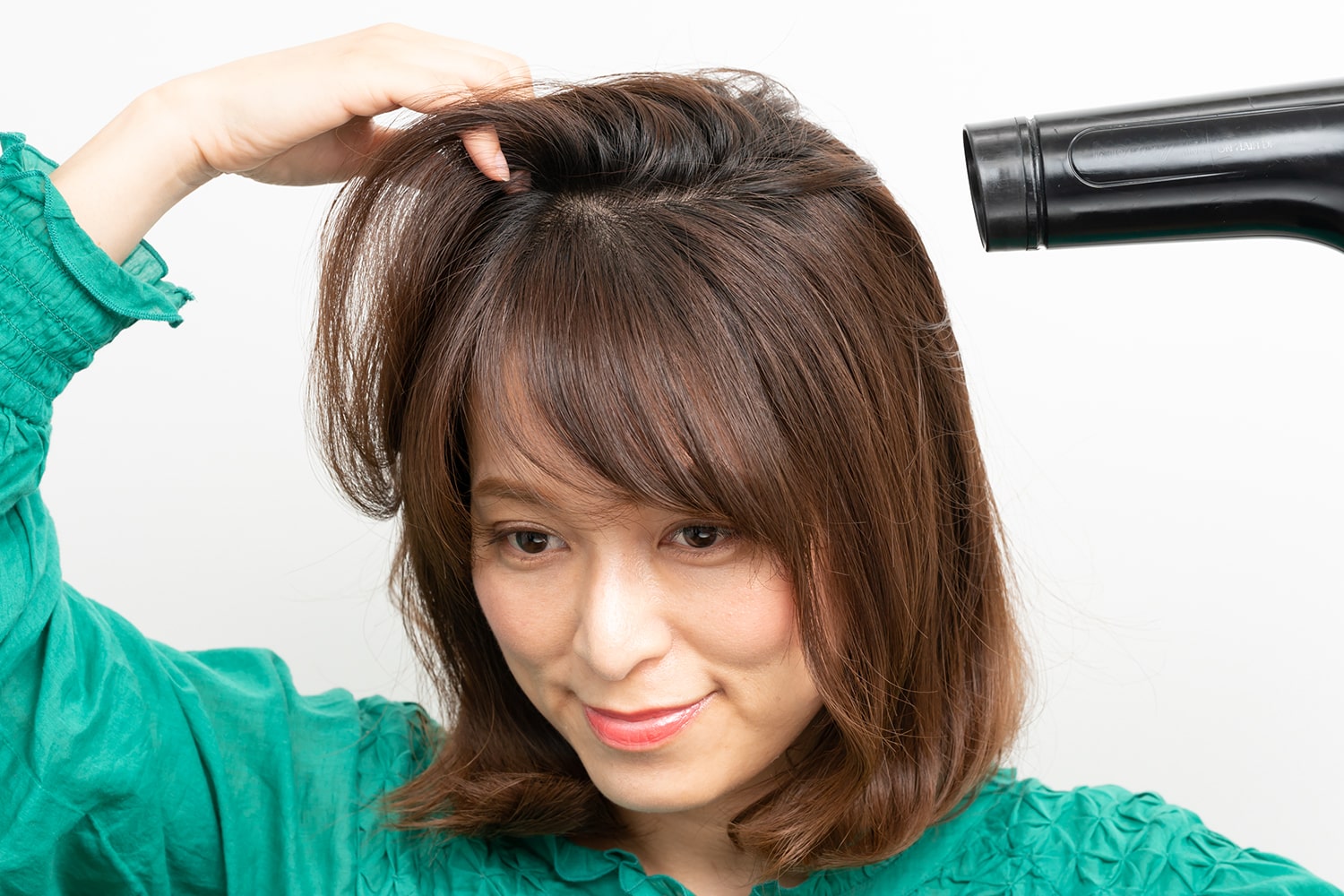 手ぐしで分け目と逆方向にとかしながら、ドライヤーをあてる。