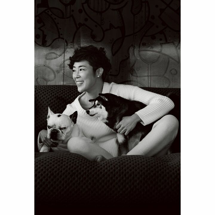 現代アートがさりげなく飾られた自宅でくつろぐ寺島さん。クールな柴犬、姫ちゃんは撫でてもらうとすっと自分の場所へ。捨ちゃんはひっついたまま。ニット￥29,000（HAUNT代官山/ゲストリスト〈HAUNT〉）、パンツ￥63,000（ストラスブルゴ〈アリクアム スポーツ＆リゾート〉）、ピアス￥340,000・リング［右手中指］￥410,000（カレラ イ カレラ）、ネックレス￥38,000・リング［右手薬指］￥46,000（ジョアドゥ トリート）、その他／私物