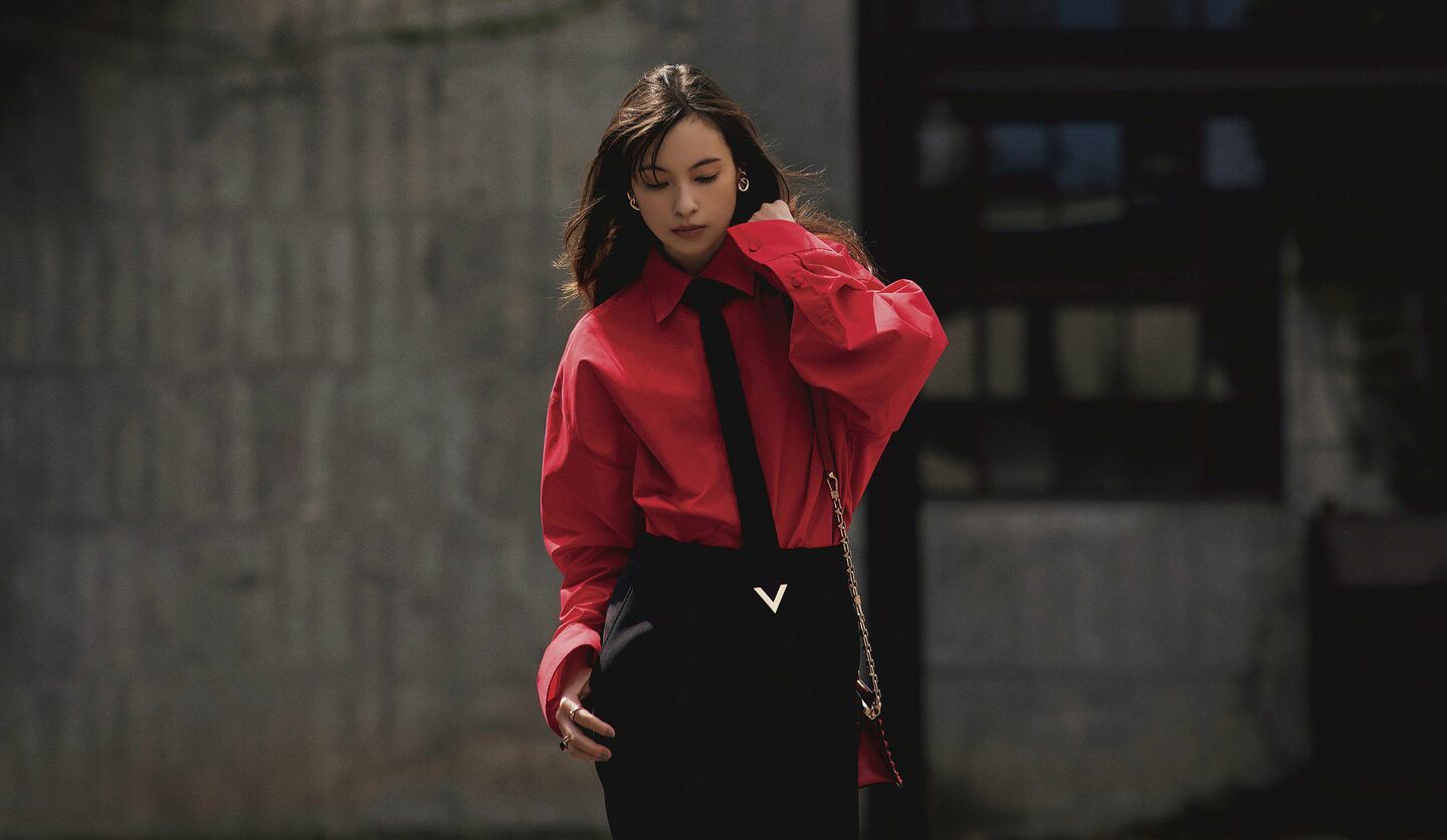 ブラックパンツにブラックタイ、赤いシャツのモデルの写真