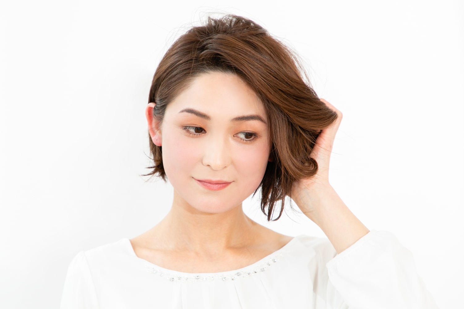 外ハネになるように毛先を持ち上げながら、バームタイプのワックスをもみ込んでラフな動きを出す。