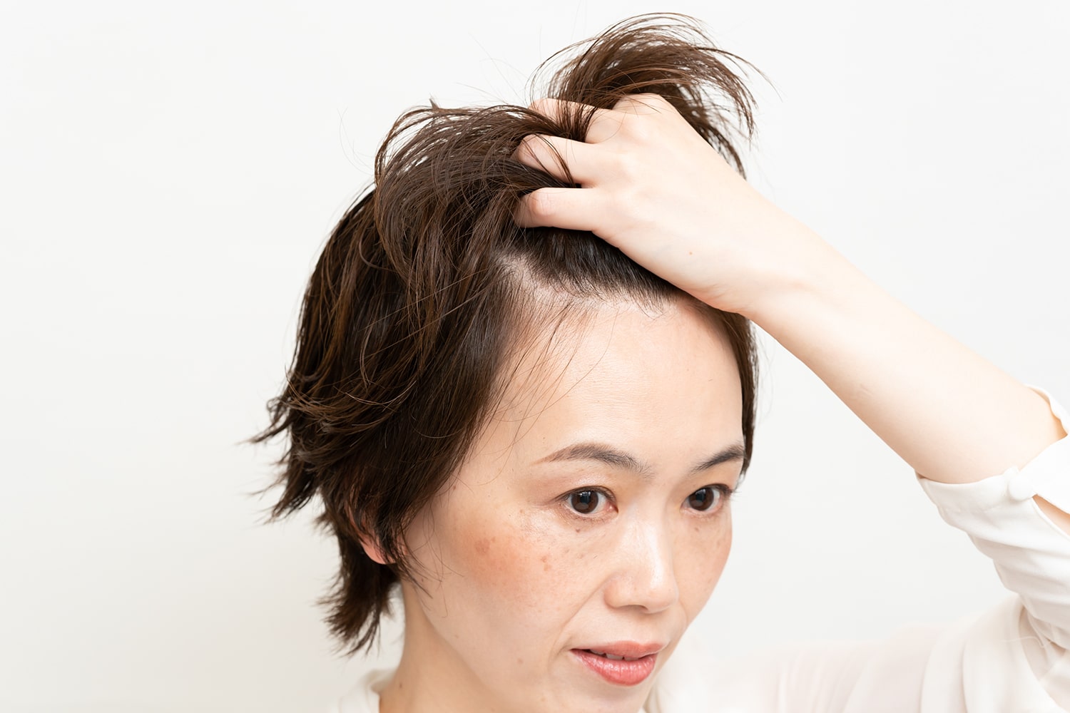 パールひと粒大のジェルを手のひらになじませたら、前髪をかき上げるようにつける。ジェルは指先につけないのがポイント。