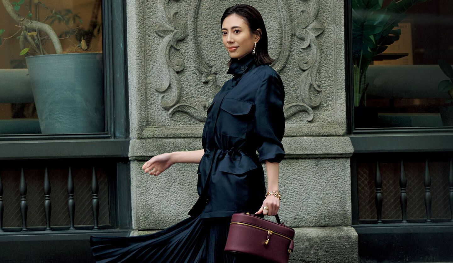 「ロロ・ピアーナ」のアウターとプリーツスカートを着用したモデル