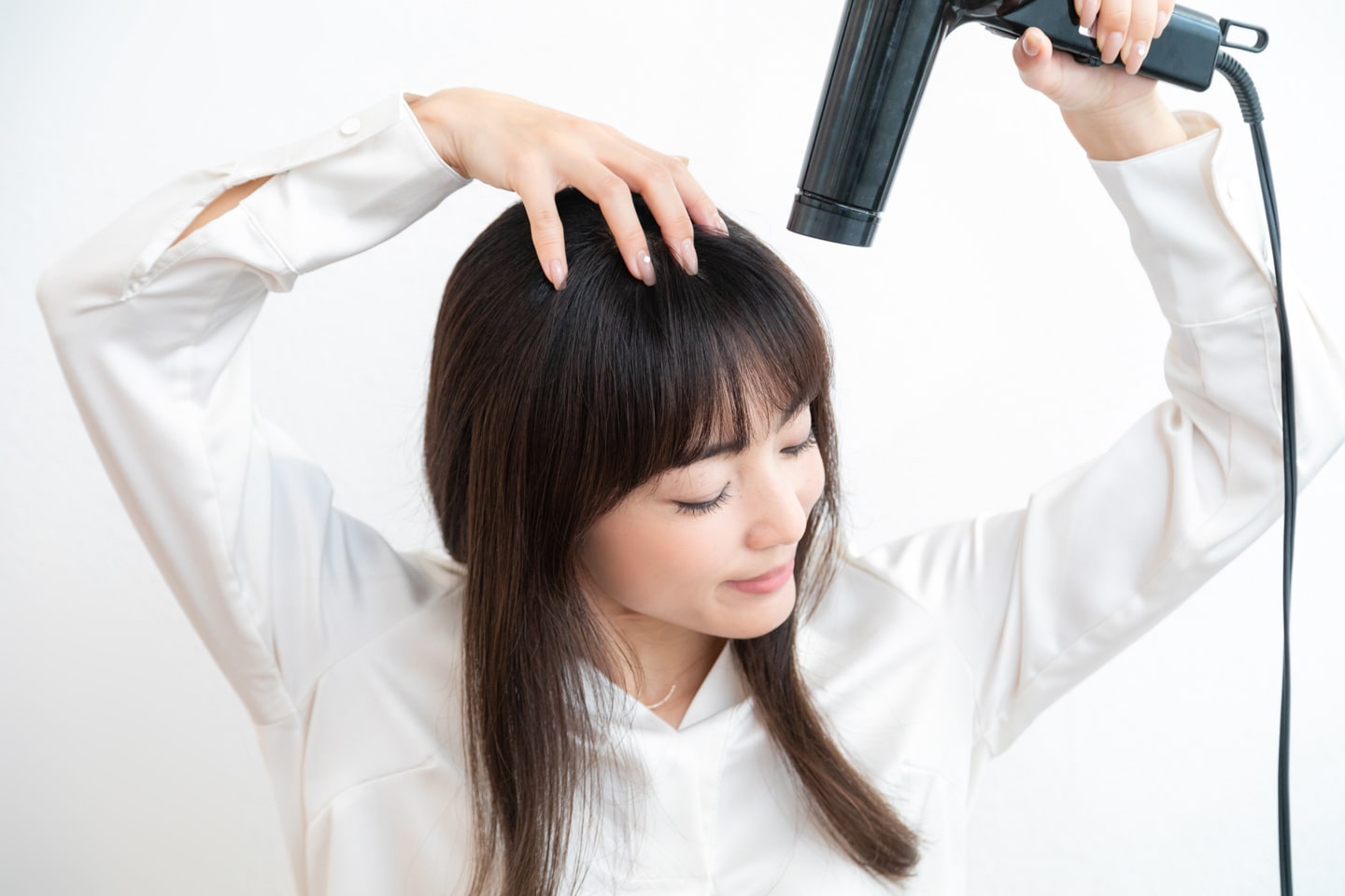 前髪が割れないように、上からドライヤーの風を当てながら、根元を擦るように左右に振って乾かす。