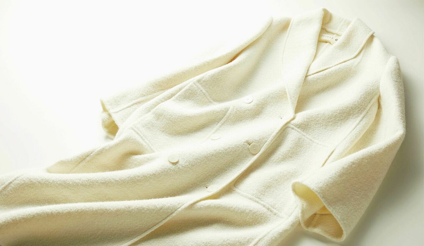 ウールアルパカの素材で作られた真っ白なロングコートの写真