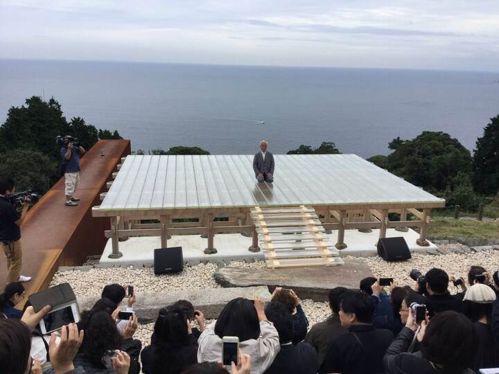 光学ガラスの舞台、これもモーレツかっこいい! 舞台に正座してご挨拶をされる杉本博司さん。左に見える鉄錆びた構造物が冬至の日の、朝日に向かってつくられた70メートルの「冬至光遙拝隧道」