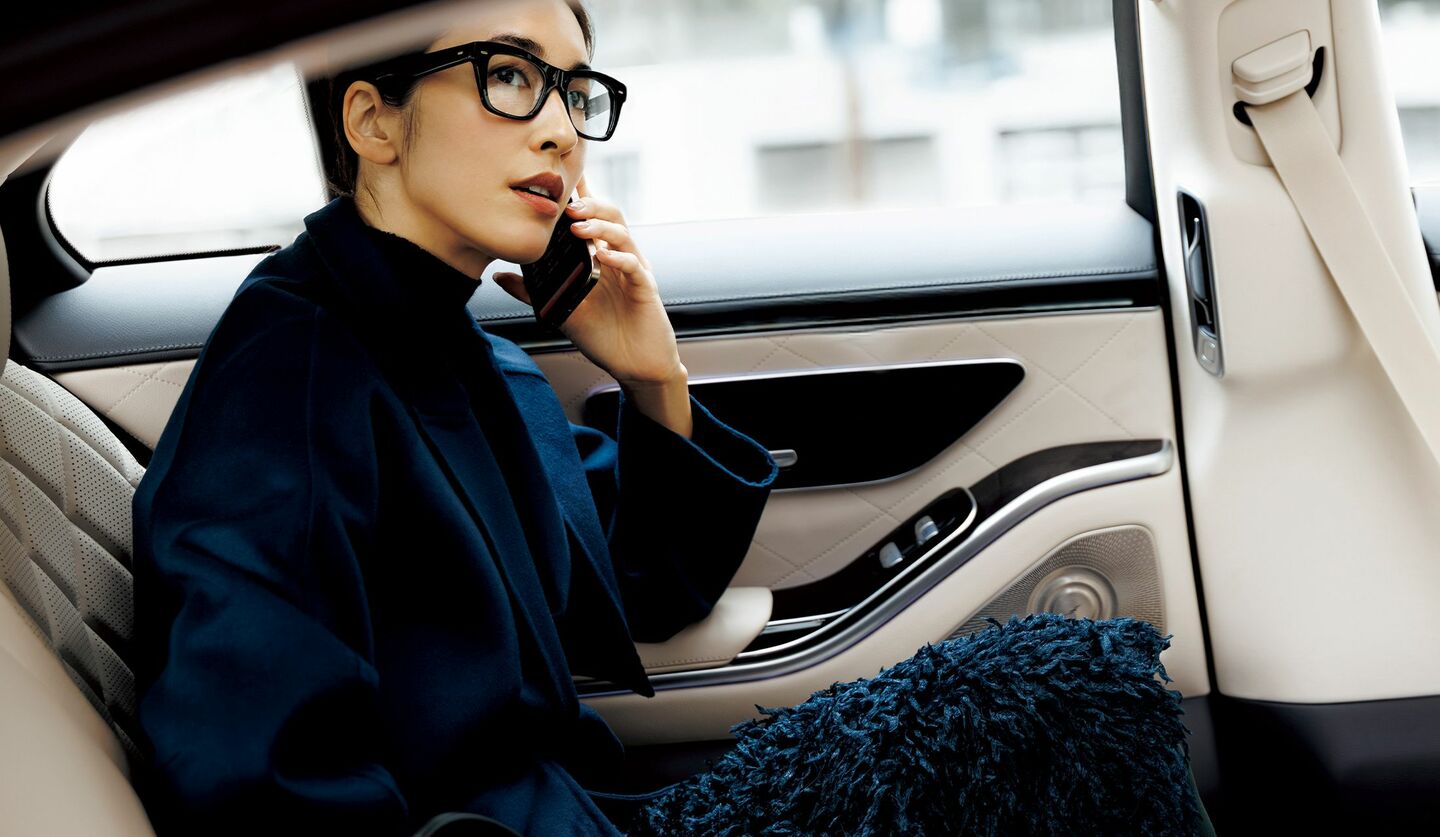 ネイビーのフリンジスカートとコートを着用して、自動車内に座るモデル