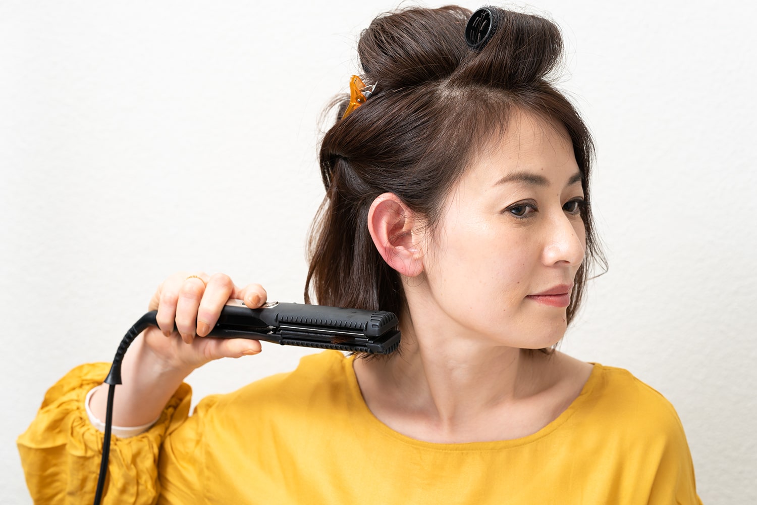 ストレートアイロンに毛束を挟んだら真っ直ぐ下におろし、毛先だけ半カールさせる。