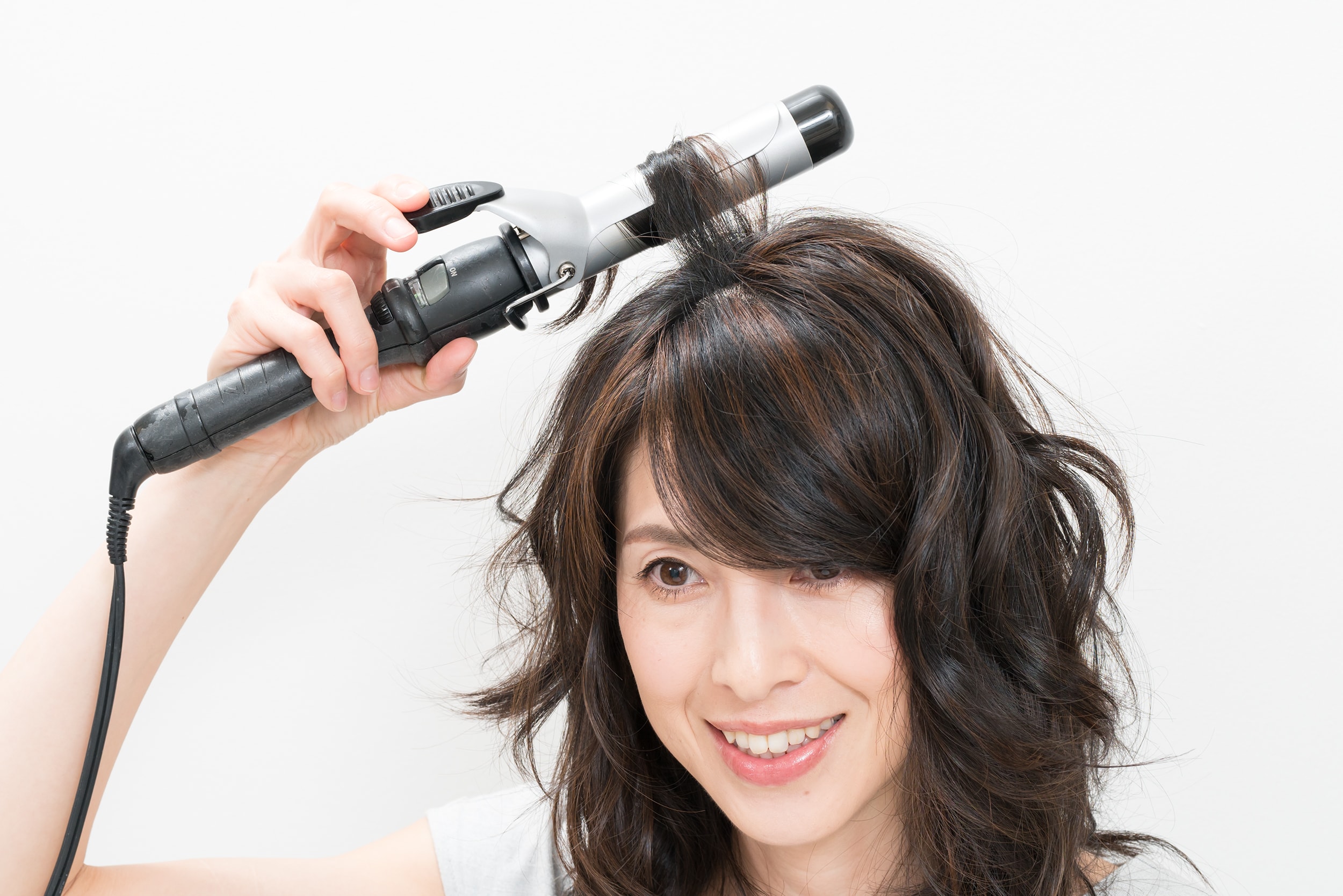 頭頂部の髪のみ、毛束を細く取ったら中間から根元に向かって、外巻き、内巻きとランダムに巻いていく。