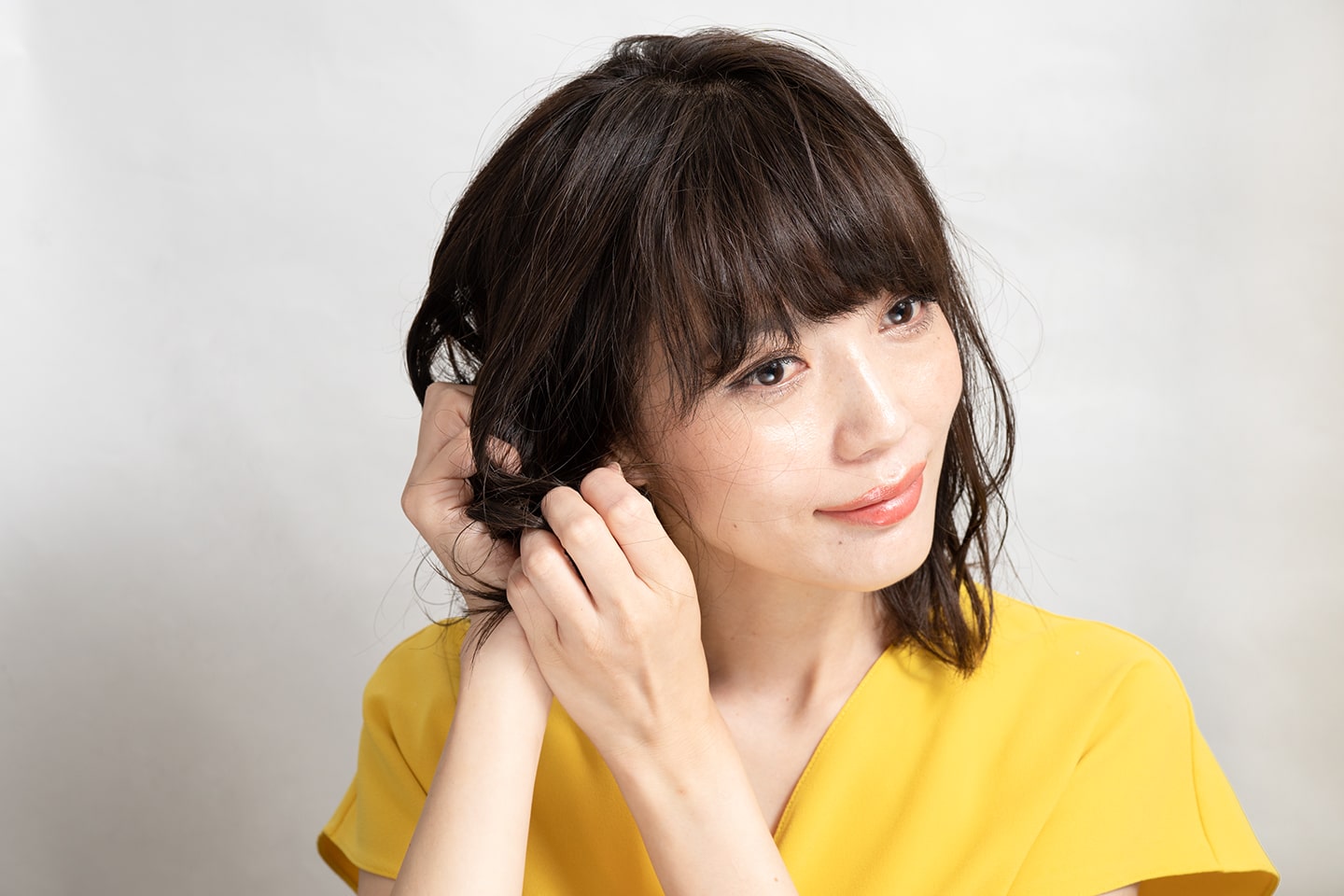 両手のひらにワックスを広げたら、耳より下の髪をクシュクシュッと握ってクセを生かすようになじませる。