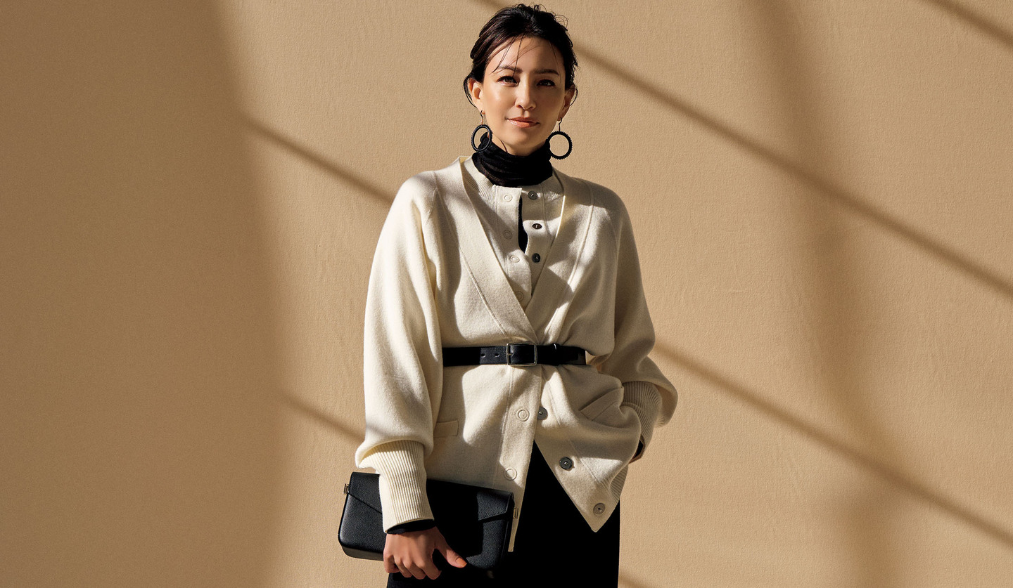 「オーヴィル」の黒のタートルニットにカーディガンを2枚重ねて着用したモデル